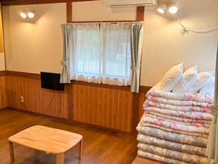 リビング外観写真、敷布団とテーブル、テレビが映っています。