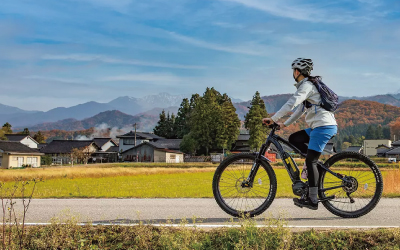 サイクリングイメージ写真。女性が田んぼ沿いを走っています。