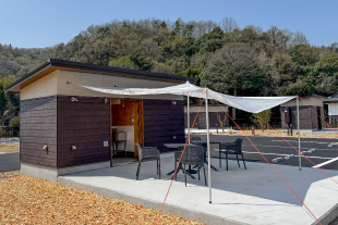 ユニットキャンプサイトに専用タープを設置し、付属のテーブルチェアを配置した様子