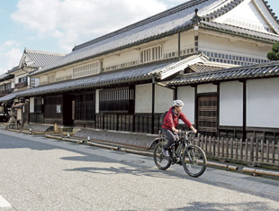 矢掛町の宿場町を1人の男性がEバイクで走っている様子