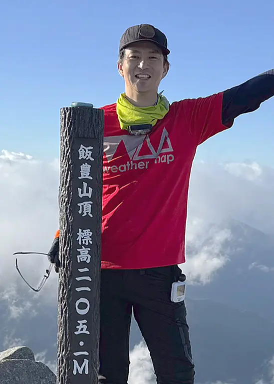 飯富山山頂で笑顔で手をふる兵頭哲二気象予報士。